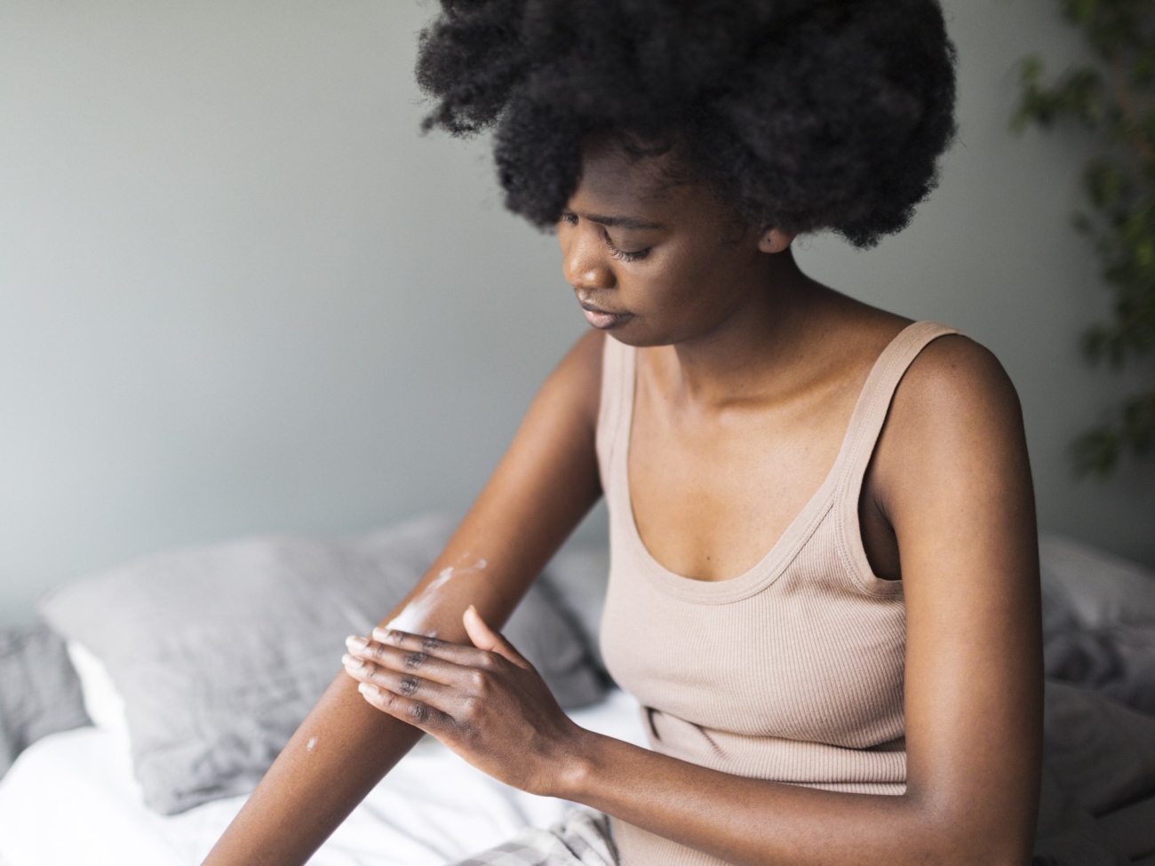Black woman applying body lotion