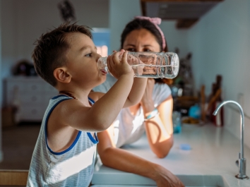 boy drinking water at kitchen sink